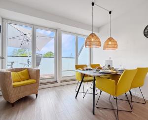 ein Esszimmer mit einem Tisch und gelben Stühlen in der Unterkunft 3002 - Grömitz in Grömitz