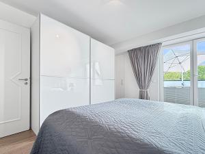 ein weißes Schlafzimmer mit einem Bett und einem Fenster in der Unterkunft 3002 - Grömitz in Grömitz + 14 Fotos