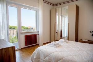 a white bedroom with a large bed and large windows at MD Beach Home in Roseto degli Abruzzi