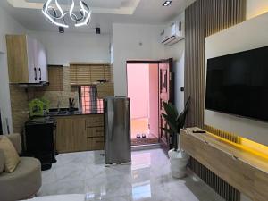 a living room with a large television and a kitchen at Cosmo haven suites in Ibadan