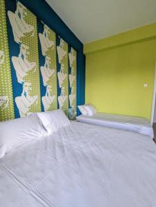 a bedroom with a white bed with a green wall at Okeania Seafront Rooms in Kamena Vourla in Kamena Vourla