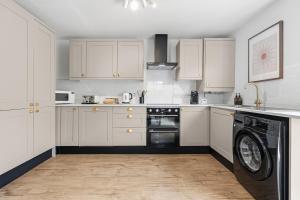 a kitchen with white cabinets and a washing machine at CHERRYTREES Beautiful 5 Bedrooms, Sleeps 9, 3 Bathrooms, Parking, Ideal for Groups and Work Stays in Corby