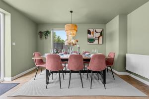 a dining room with a table and pink chairs at CHERRYTREES Beautiful 5 Bedrooms, Sleeps 9, 3 Bathrooms, Parking, Ideal for Groups and Work Stays in Corby