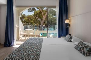 una camera da letto con un letto e un balcone con un tavolo di Alcanada Golf Hotel a Port d'Alcudia Altre 52 foto