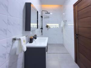 a white bathroom with a sink and a mirror at Horizon Apartment at THE HIDDEN DOMUS I Pool View in Accra +18 photos
