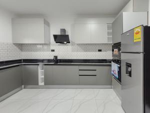 a kitchen with white cabinets and a refrigerator at Horizon Apartment at THE HIDDEN DOMUS I Pool View in Accra