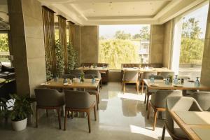 a restaurant with wooden tables and chairs and a large window at Raj Regent Manarcadu in Kanjirapalli