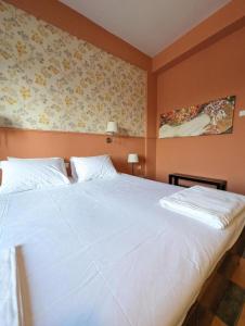 a bedroom with a large white bed with floral wallpaper at Okeania Seafront Rooms in Kamena Vourla in Kamena Vourla