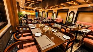 a restaurant with tables and chairs in a room at Hotel Sainik Grand in Varanasi
