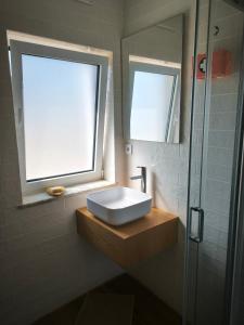 a bathroom with a sink and a window and a shower at A Quinta in Vila Nova de Milfontes