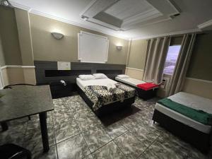 a small room with two beds and a window at Hotel Vitória de Santos in Santos