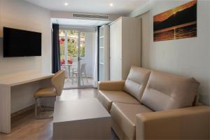 un soggiorno con divano e televisore di Alcanada Golf Hotel a Port d'Alcudia