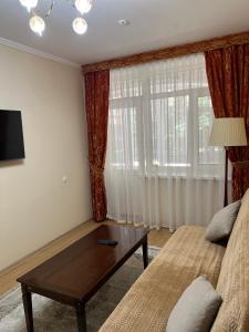 a living room with a couch and a coffee table at АпартаментРадугаВест1 in Koshkolʼ