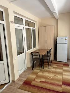 a kitchen with a table and chairs and a refrigerator at АпартаментРадугаВест1 in Koshkolʼ +6 photos