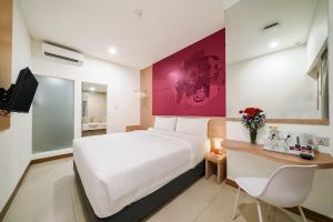 a hotel room with a large white bed and a desk at favehotel Pluit Junction in Jakarta +17 photos