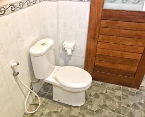 baño con aseo blanco y puerta de madera en Sapta House en Ubud