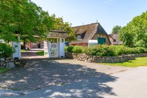 a house with a white gate and a stone wall at Wrixum - Herrenhof Nr 7 Leevhüs in Wrixum
