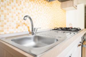 eine Edelstahlspüle in einer Küche mit Herd in der Unterkunft Db Apartment in Giurdignano + 48 Fotos
