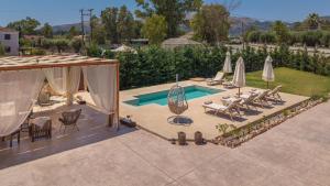 a backyard with a pool with chairs and umbrellas at Villa Nicoldia with private pool near Laganas in Laganas