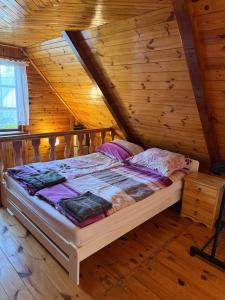 a bedroom with a bed in a wooden cabin at Domki Pod Lasem in Macharce