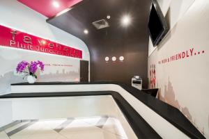 a lobby with a tv and flowers on a wall at favehotel Pluit Junction in Jakarta
