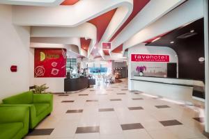 a lobby with a green couch and a counter at favehotel Pluit Junction in Jakarta