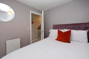 a bedroom with a white bed with a red pillow at Autumn Heights Apartments in Telford