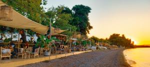 a group of tables and chairs on the side of a beach at Ronzi Apartments in Kamena Vourla