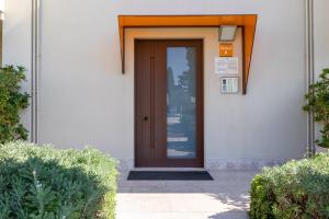 a brown door on a white building with bushes at Corte Fasanella 33 in Toscolano Maderno +24 photos