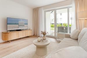 a white living room with a tv and a large window at Baltic Studio No 5 in Scharbeutz
