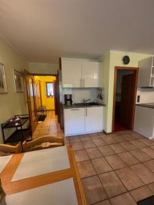 a kitchen and living room with white cabinets and a tile floor at Ferienwohnung Hunsrückblick in Thalfang