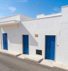 two blue doors on the side of a white building at SALENTO d' aMARE in Torre Lapillo