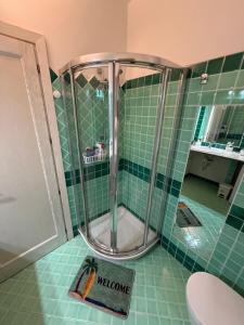 a shower in a bathroom with green tiles at Benni Surf House in San Pasquale
