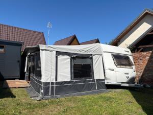 a white rv parked in a yard next to a house at Platin Pure in Jastarnia