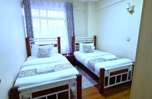 two twin beds in a room with a window at The African Artisan 3BR Apartment in Nairobi