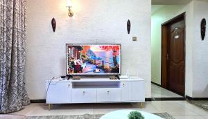 a tv sitting on top of a white cabinet in a room at The African Artisan 3BR Apartment in Nairobi