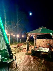 a deck with a green umbrella and a hot tub at Chalé Paraíso in Nerópolis