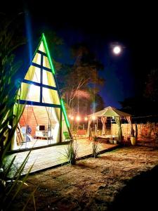 a triangular building with a green light on it at night at Chalé Paraíso in Nerópolis