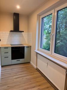 a kitchen with a stove and two windows at Ruheoase am Stadtrand in Buchholz in der Nordheide +2 photos