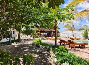 a resort with a pool and benches and trees at One Love Garden Villas Paje in Kiganga