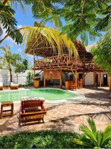 a resort with a swimming pool with a thatched roof at One Love Garden Villas Paje in Kiganga