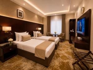 a hotel room with two beds and a flat screen tv at هندباء Hindibaa in Mecca