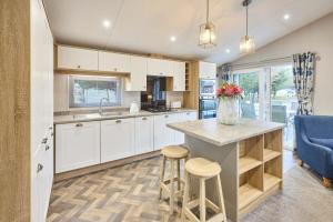 a kitchen with white cabinets and a counter with stools at The Haven Lodge with Hot Tub in York