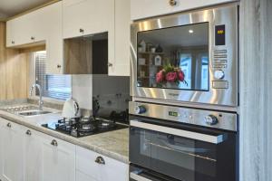 a kitchen with a stove and a microwave at The Haven Lodge with Hot Tub in York