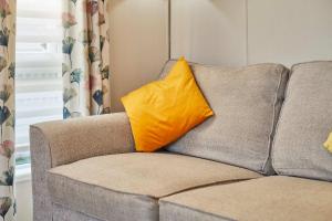 a yellow pillow sitting on top of a couch at Penny Lodge with Hot Tub in Malton