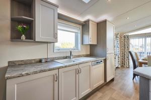 a kitchen with white cabinets and a sink and a window at Penny Lodge with Hot Tub in Malton +24 photos