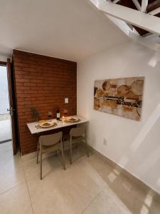 a dining room with a table and chairs and a brick wall at Loft Novo, Duplex, bem ventilado in Aparecida de Goiânia