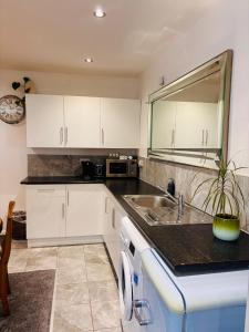 a kitchen with white cabinets and a sink at Sleeps 5 Free Parking Fast WiFi Near Hillsborough Easy Access to Sheffield City Centre and Peak District in Hillsborough