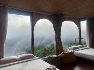 two beds in a room with a large window at Mimoza homestay cầu đất in Xuân Trường +6 photos