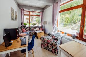 ein Wohnzimmer mit einem Schreibtisch und einem Computer auf einem Tisch in der Unterkunft Instytut Zdrowia Sofra FIT & SPA in Karpacz